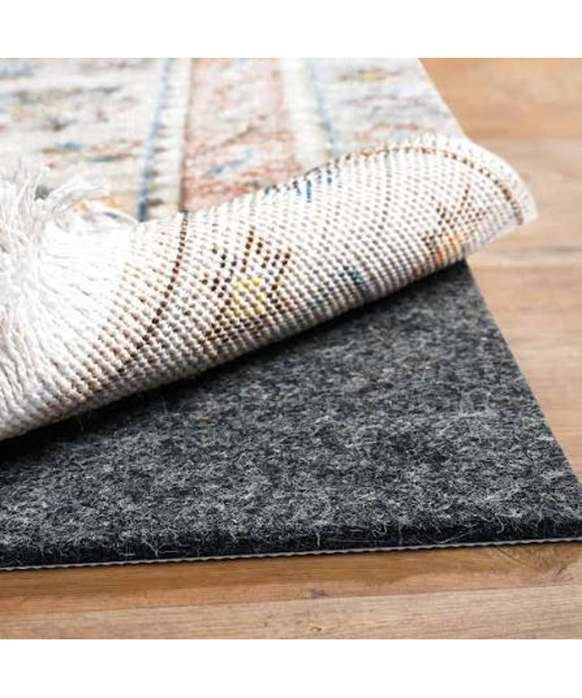Close-up of a roll of gray underlay for flooring on a wooden floor.